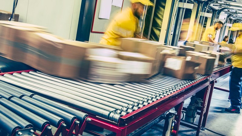 $5 parcel tax: warehouse workers sorting packages on conveyor belt